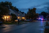 Suburban residential street with house numbers and front doors visible at evening time