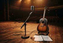 Vintage microphone and acoustic guitar on stage with warm lighting symbolizing country music legacy