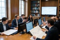 Economists reviewing economic data and charts in a professional conference room setting