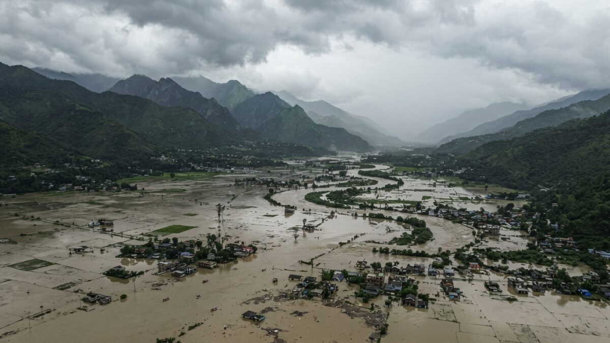 Aerial photograph showing extensive flooding in a Himalayan valley with submerged structures and agricultural land