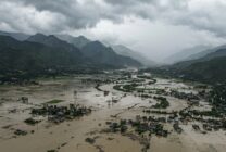 Aerial photograph showing extensive flooding in a Himalayan valley with submerged structures and agricultural land