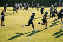 Football players practicing on training field during preseason evaluation period