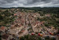 Aerial view showing tornado damage to homes in a French village with scattered debris and emergency response vehicles