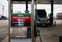 Diesel fuel pump display showing prices approaching six dollars per gallon with truck in background